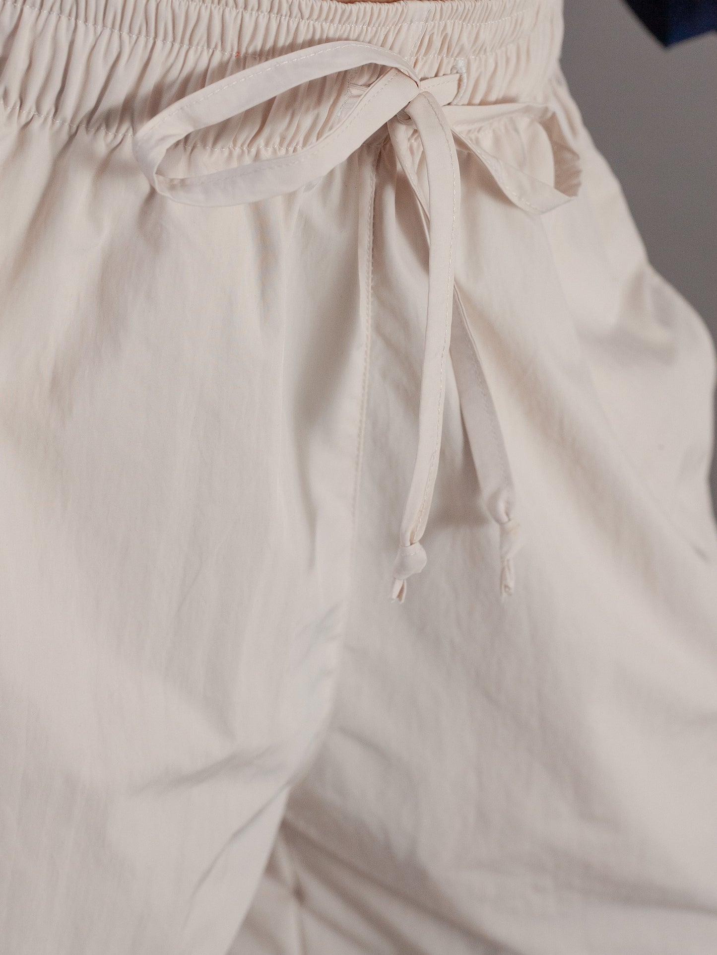 Close-up of beige pants with a drawstring waistband.