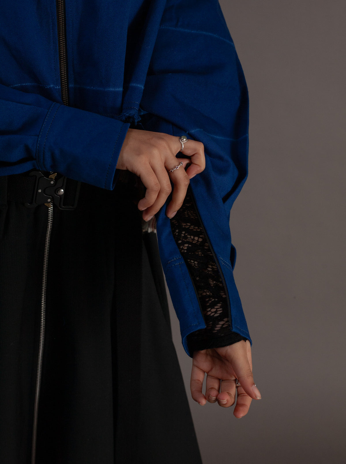 Person wearing a blue jacket with black mesh sleeves against a gray background