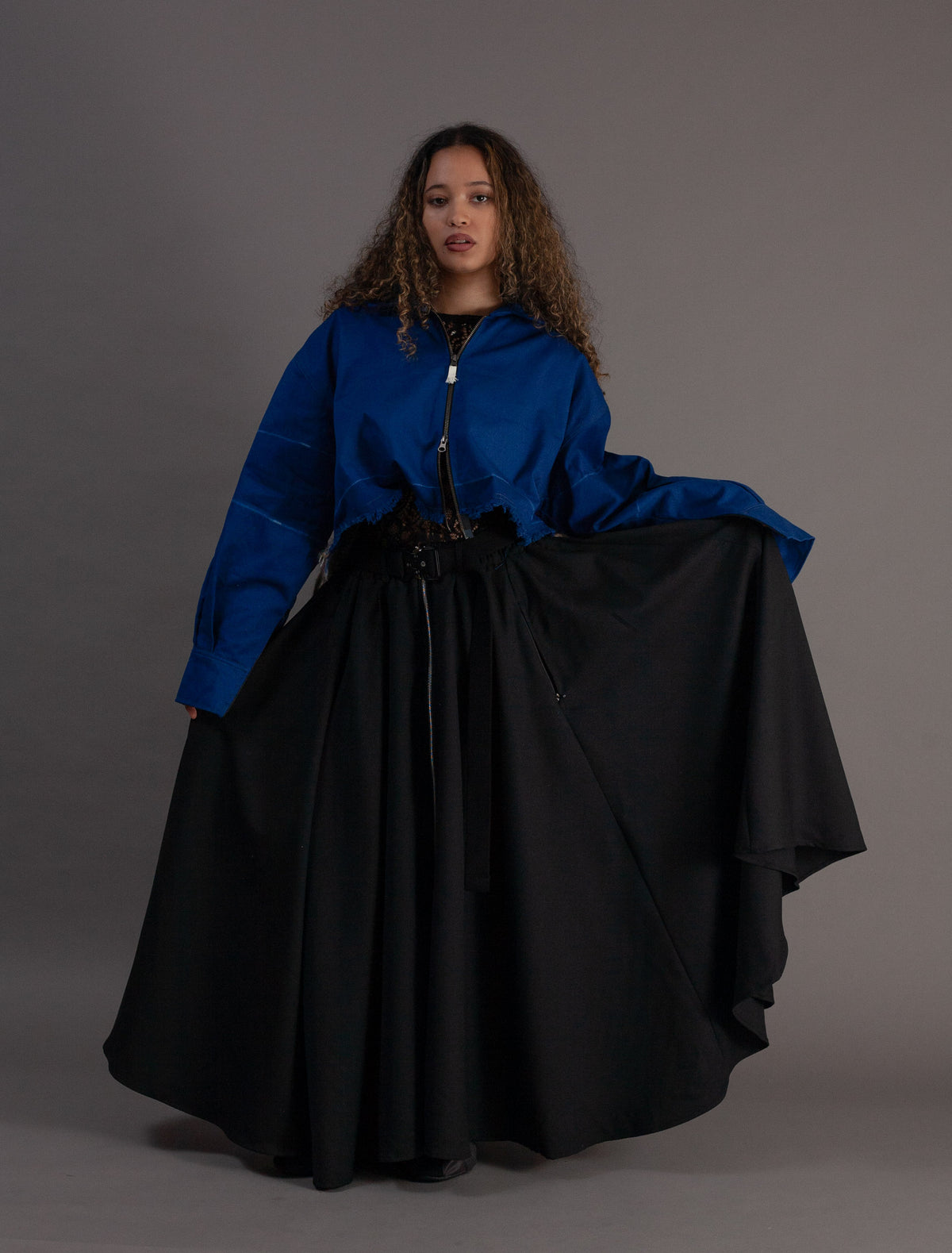Woman wearing a blue jacket and black skirt against a gray background