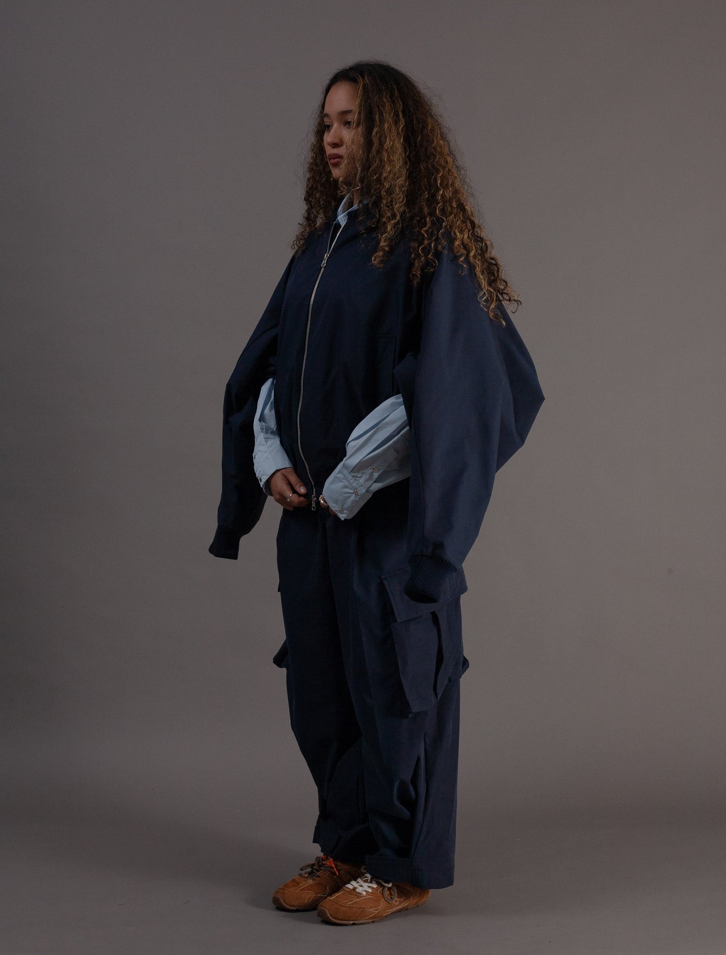 Person wearing a dark blue outfit with a gray background