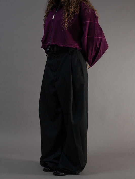 Person wearing a purple top and black pants against a grey background