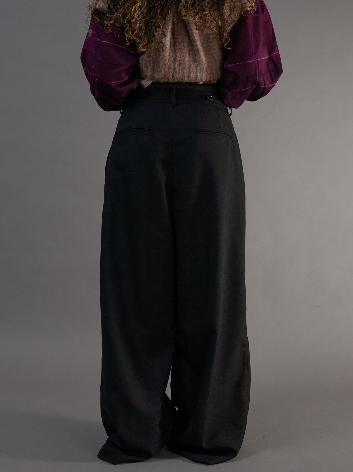 Person wearing a purple blouse and black adjustable wide-leg pants