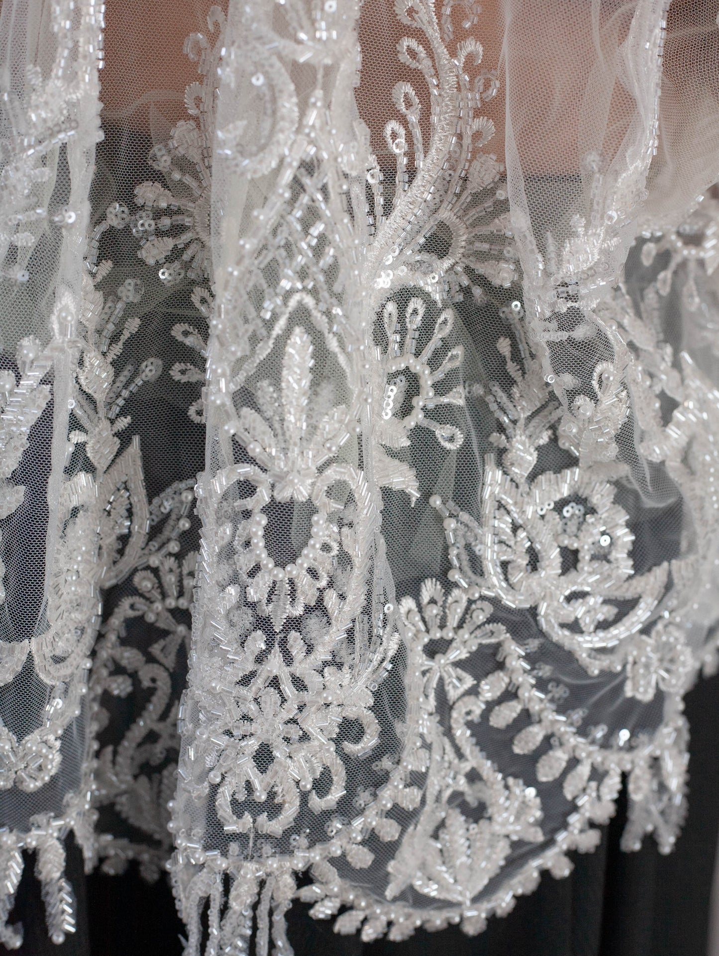 Close-up of intricate lace fabric with white embroidery on a black background