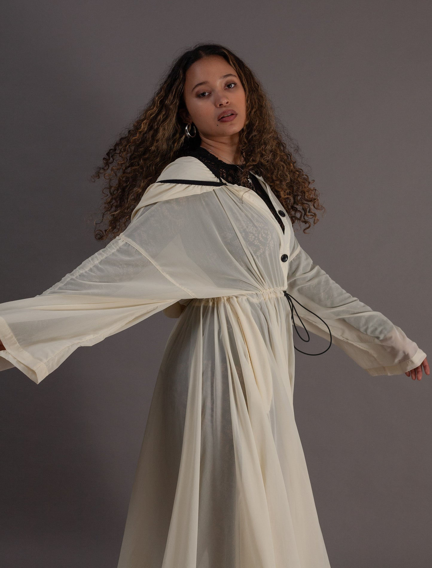 Person wearing a long, light-colored coat with black buttons