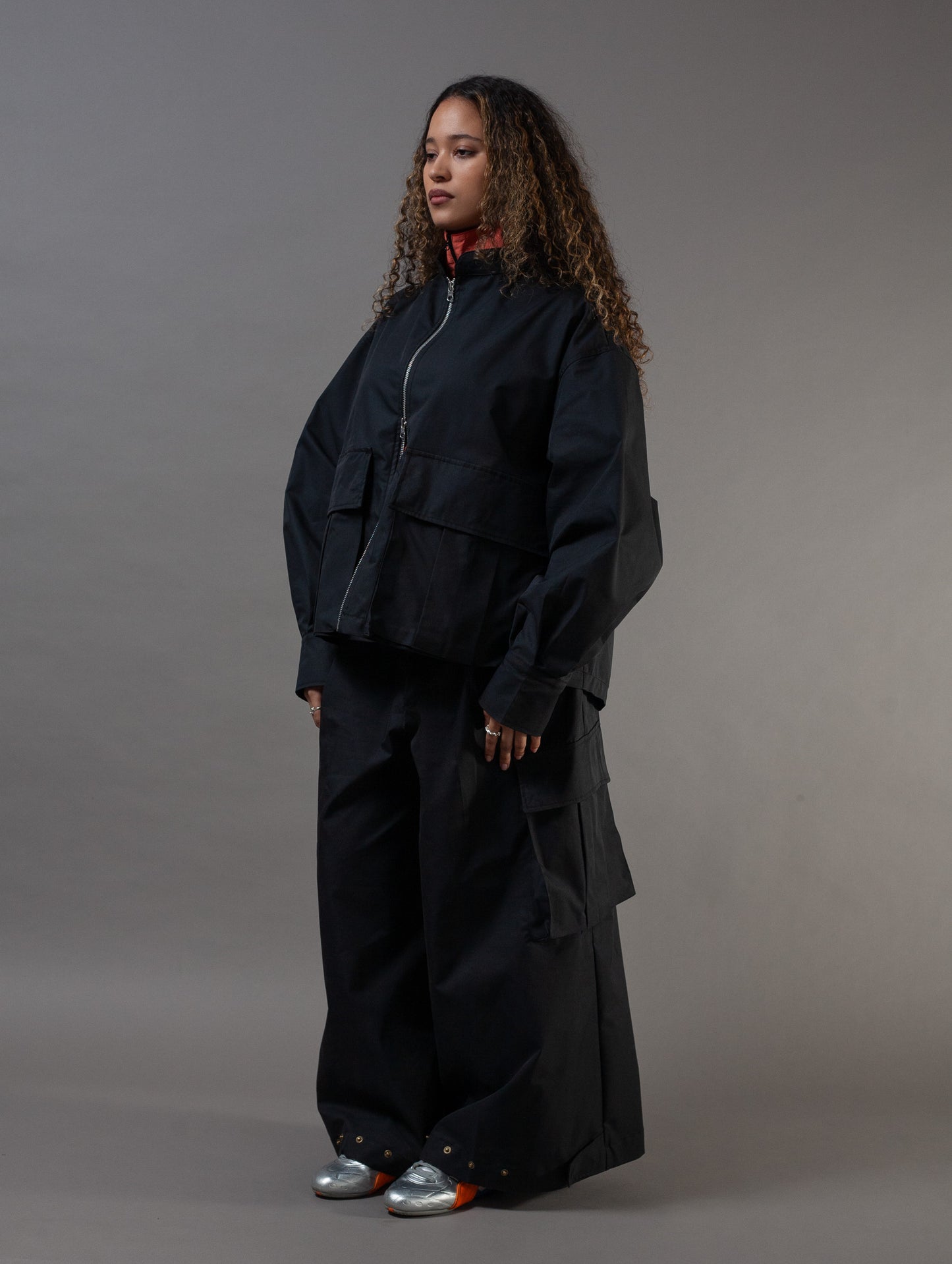 Person wearing a black outfit against a gray background