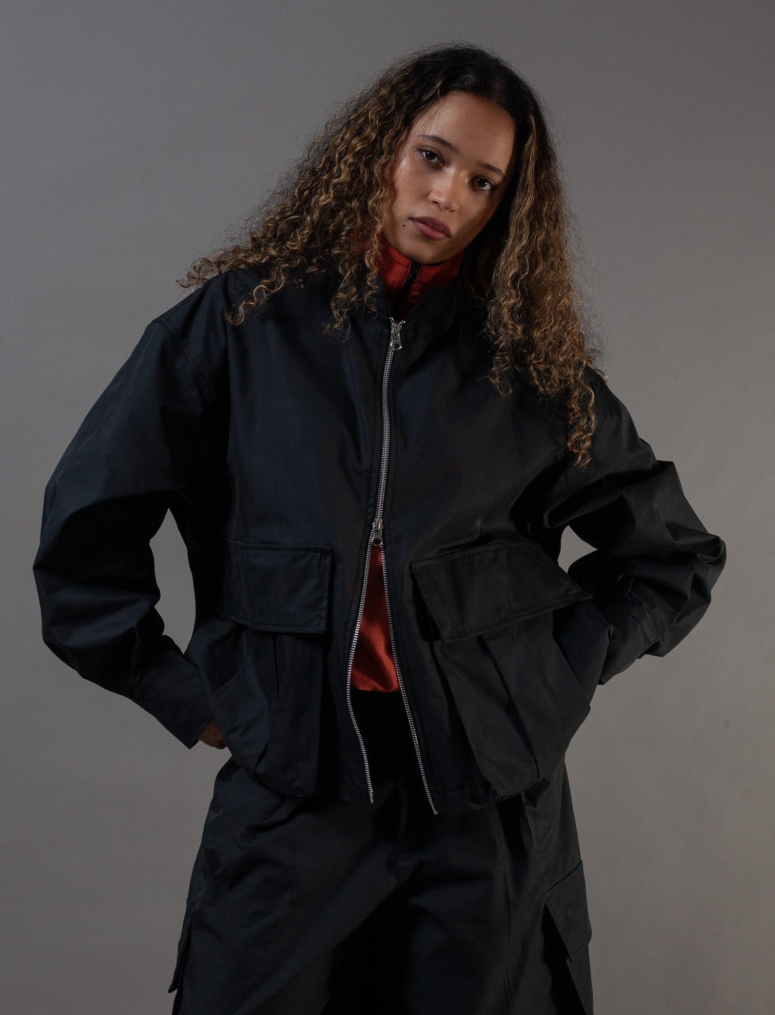 Person wearing a black outfit against a gray background