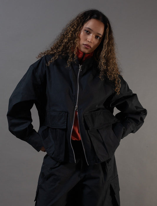 Person wearing a black outfit against a gray background