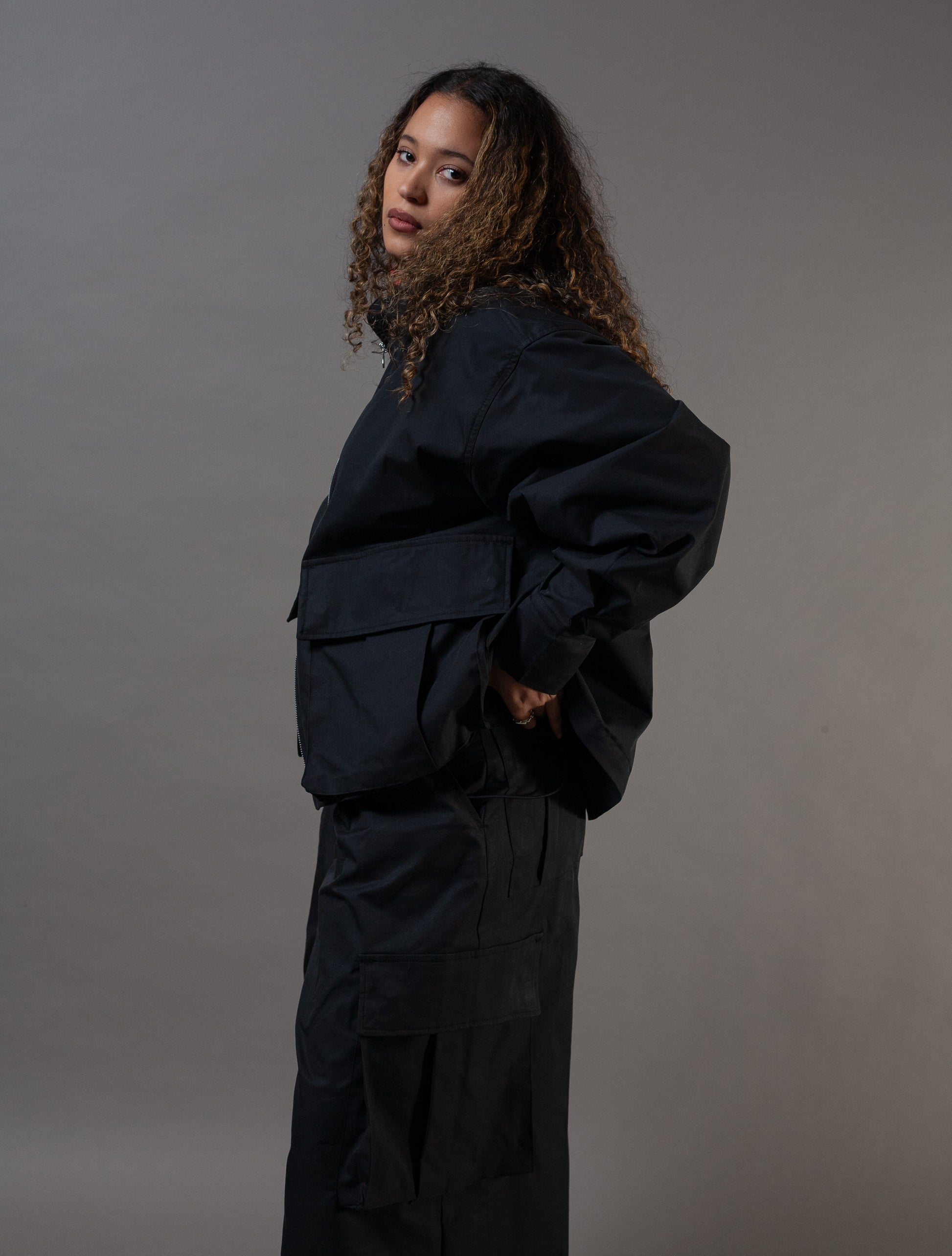 Person wearing a black outfit against a gray background