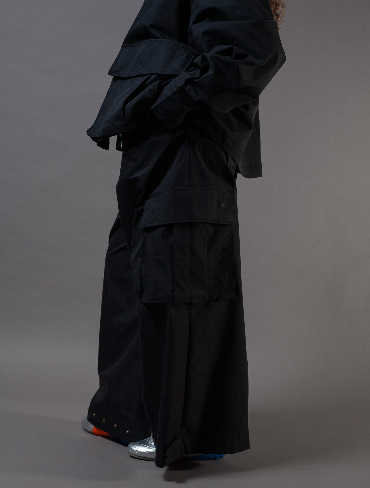 Person wearing a black outfit with wide-leg pants on a gray background
