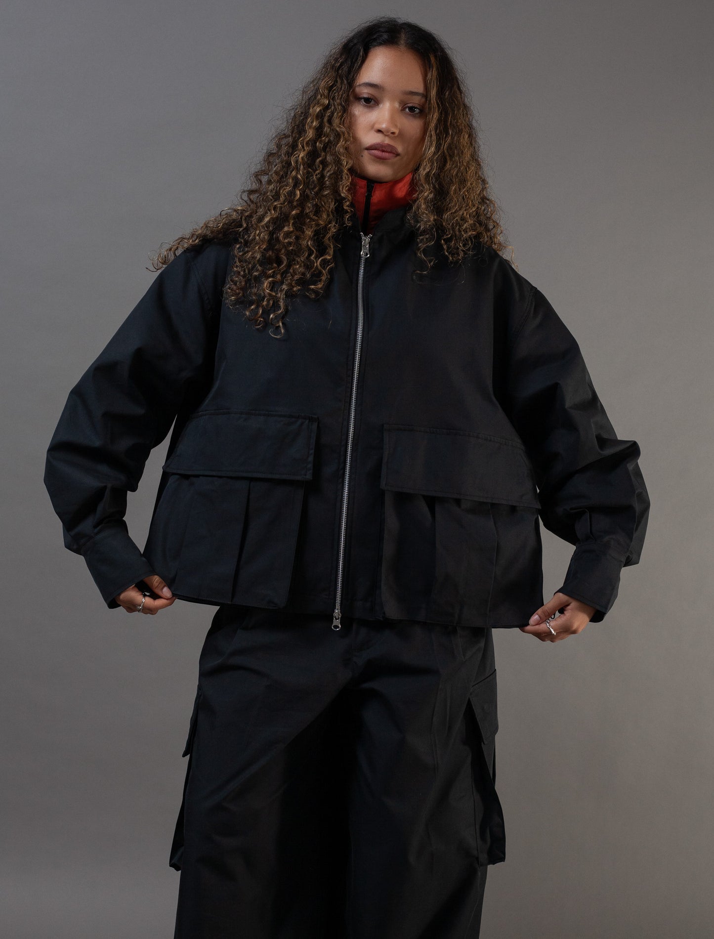 Person wearing a black jacket and pants on a gray background