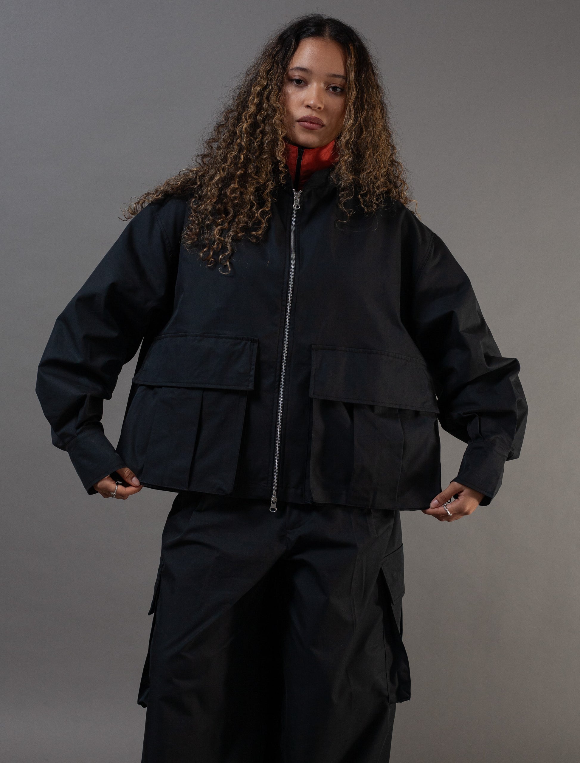 Person wearing a black jacket and pants on a gray background