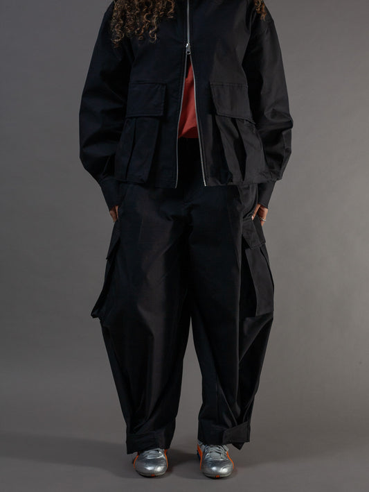 Person wearing a black jacket and pants on a gray background