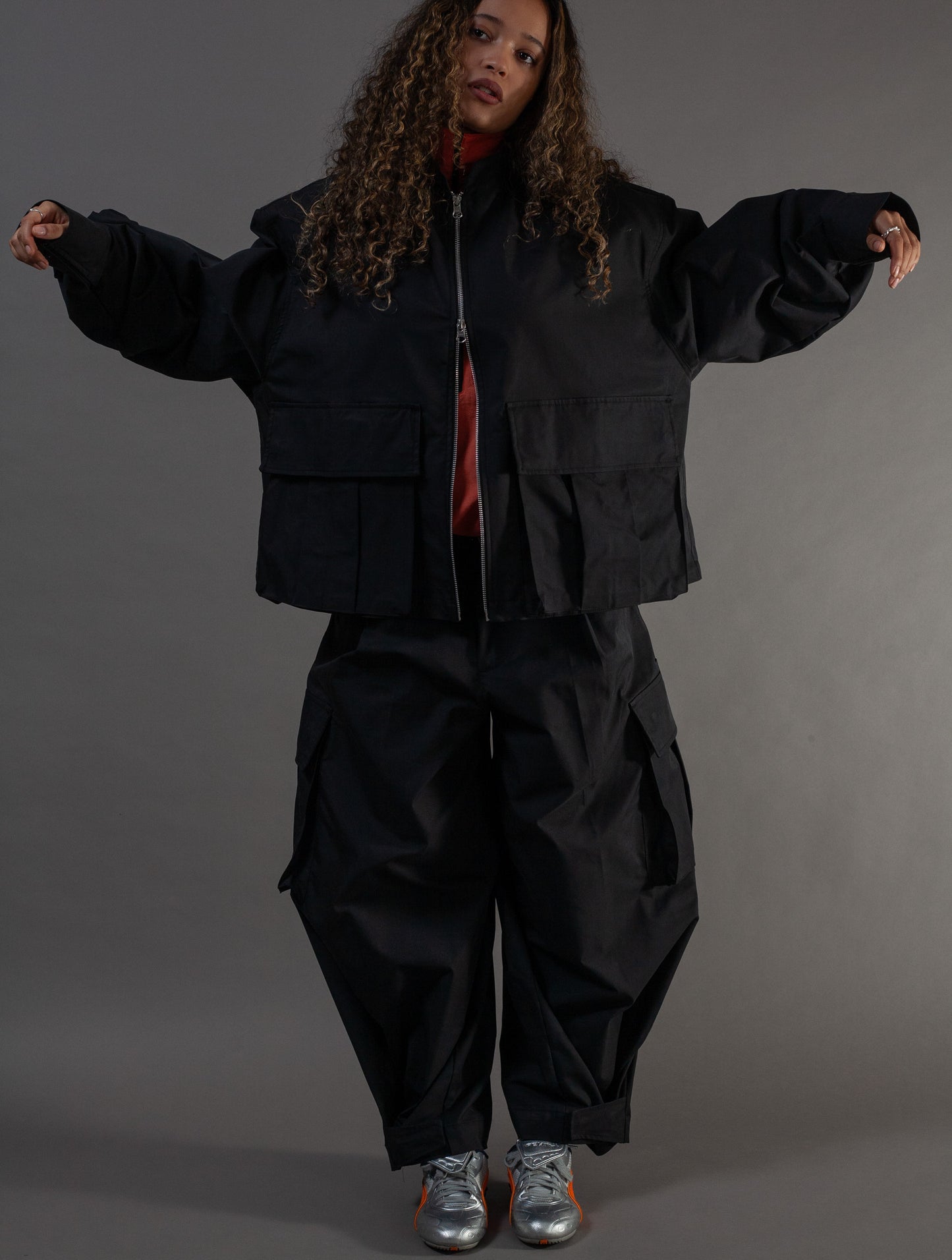 Person wearing a black outfit with a jacket and pants on a gray background