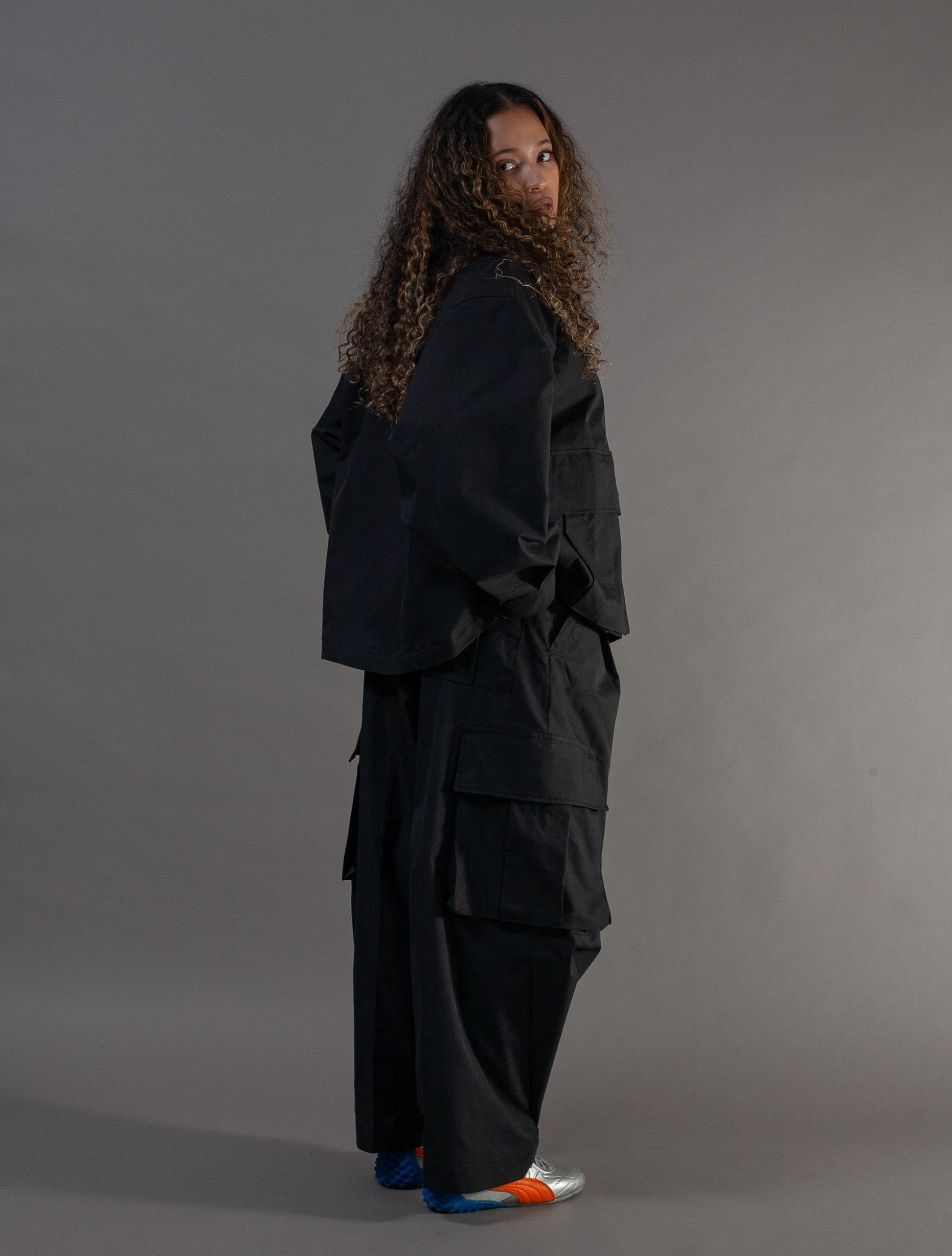 Person wearing a black outfit with layered design on a gray background
