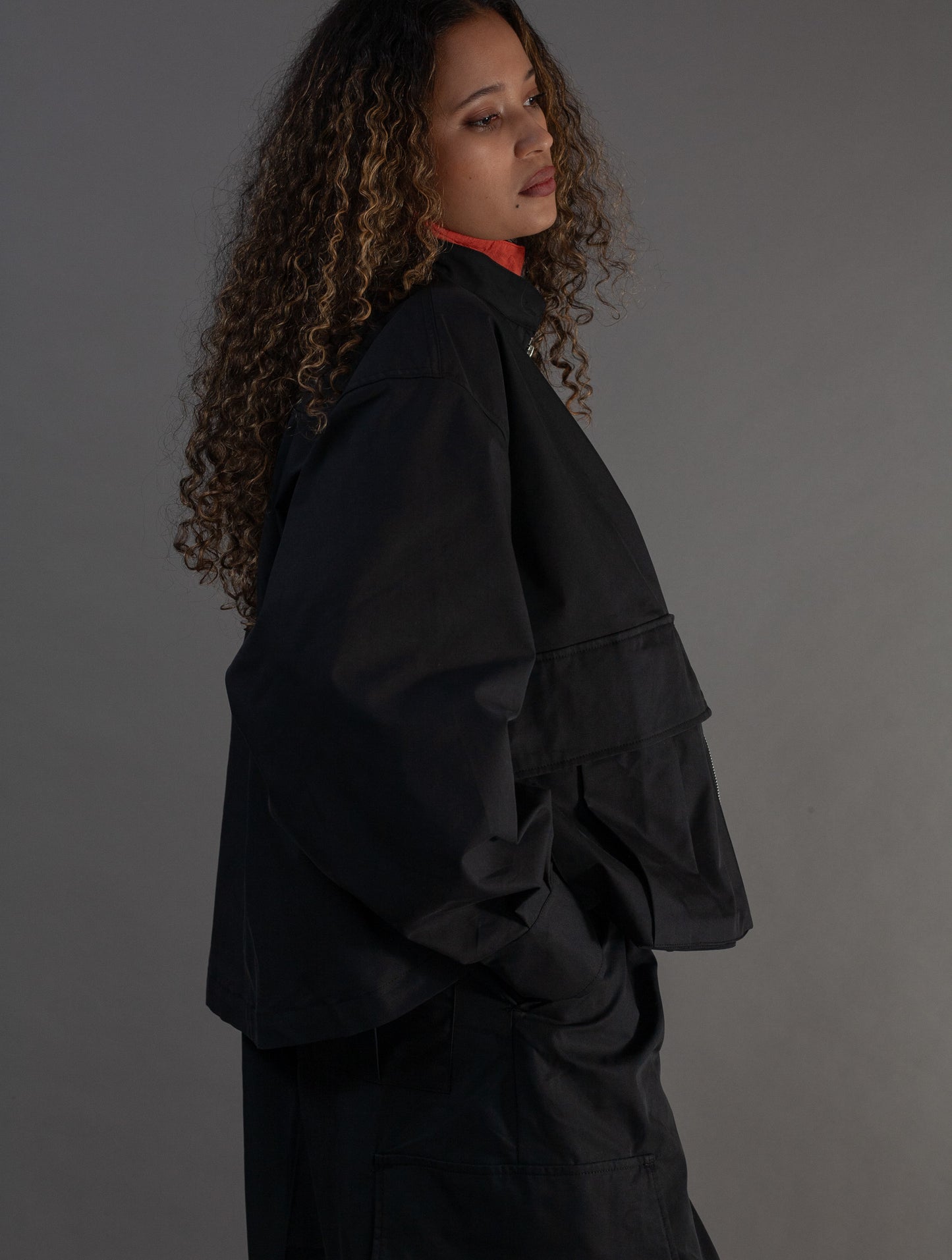 Person wearing a black jacket against a gray background