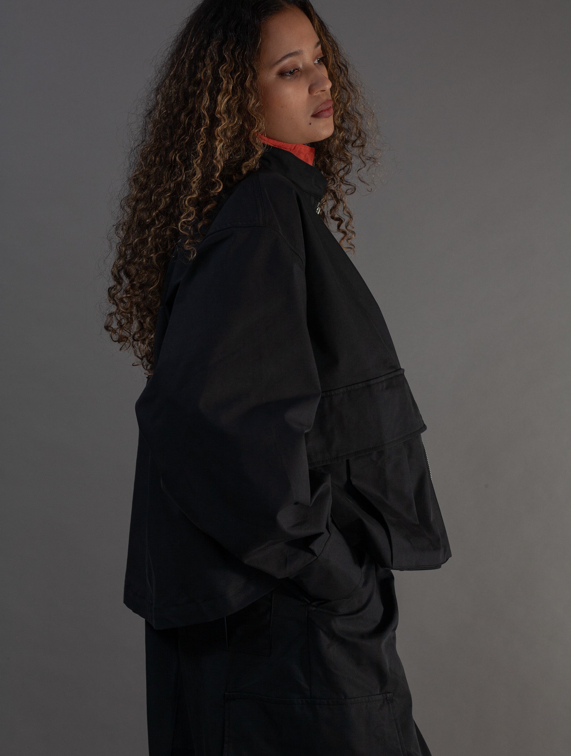 Person wearing a black jacket against a gray background