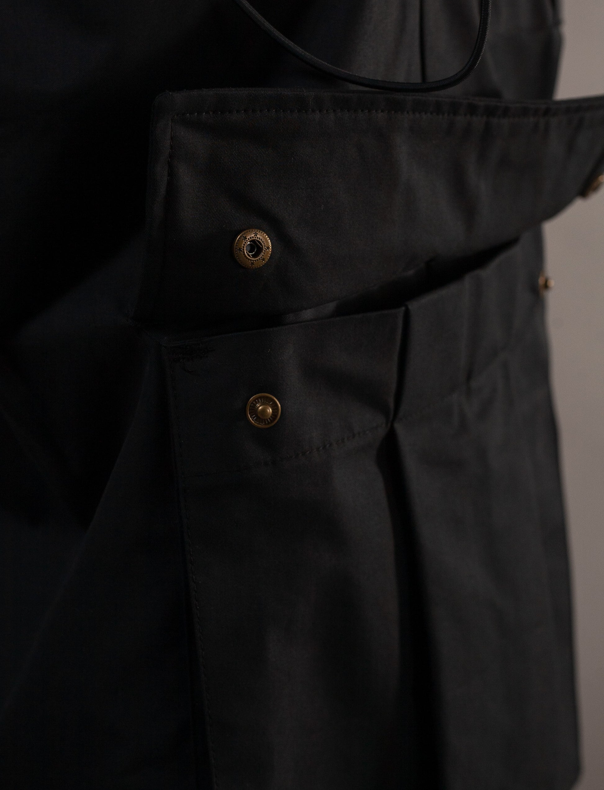 Close-up of a 3D pockett with gold buttons on a plain background