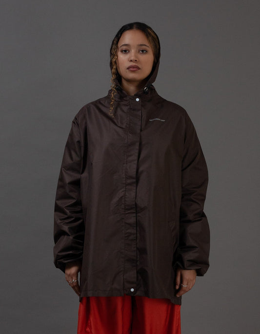 Person wearing a dark brown jacket and orange pants on a gray background