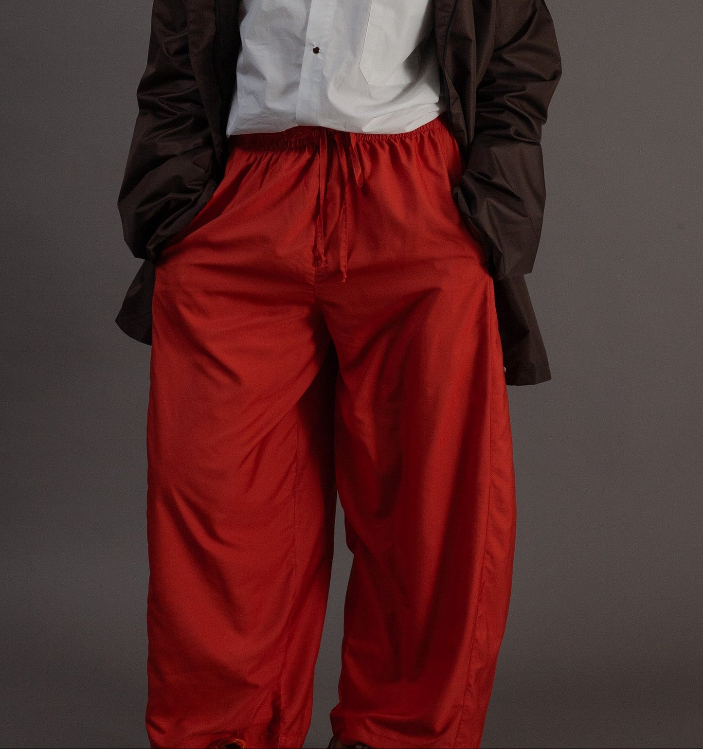 Person wearing a white shirt and orange pants on a gray background