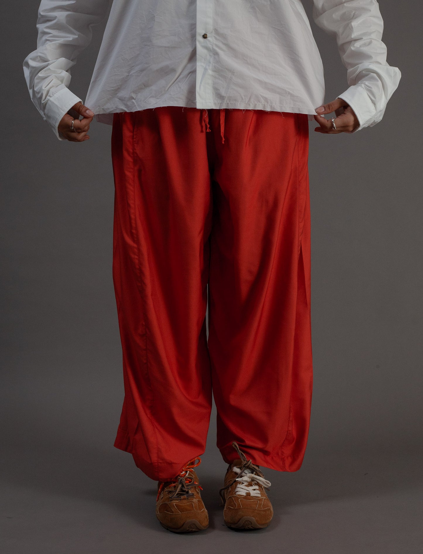 Person wearing a white shirt and orange pants on a gray background