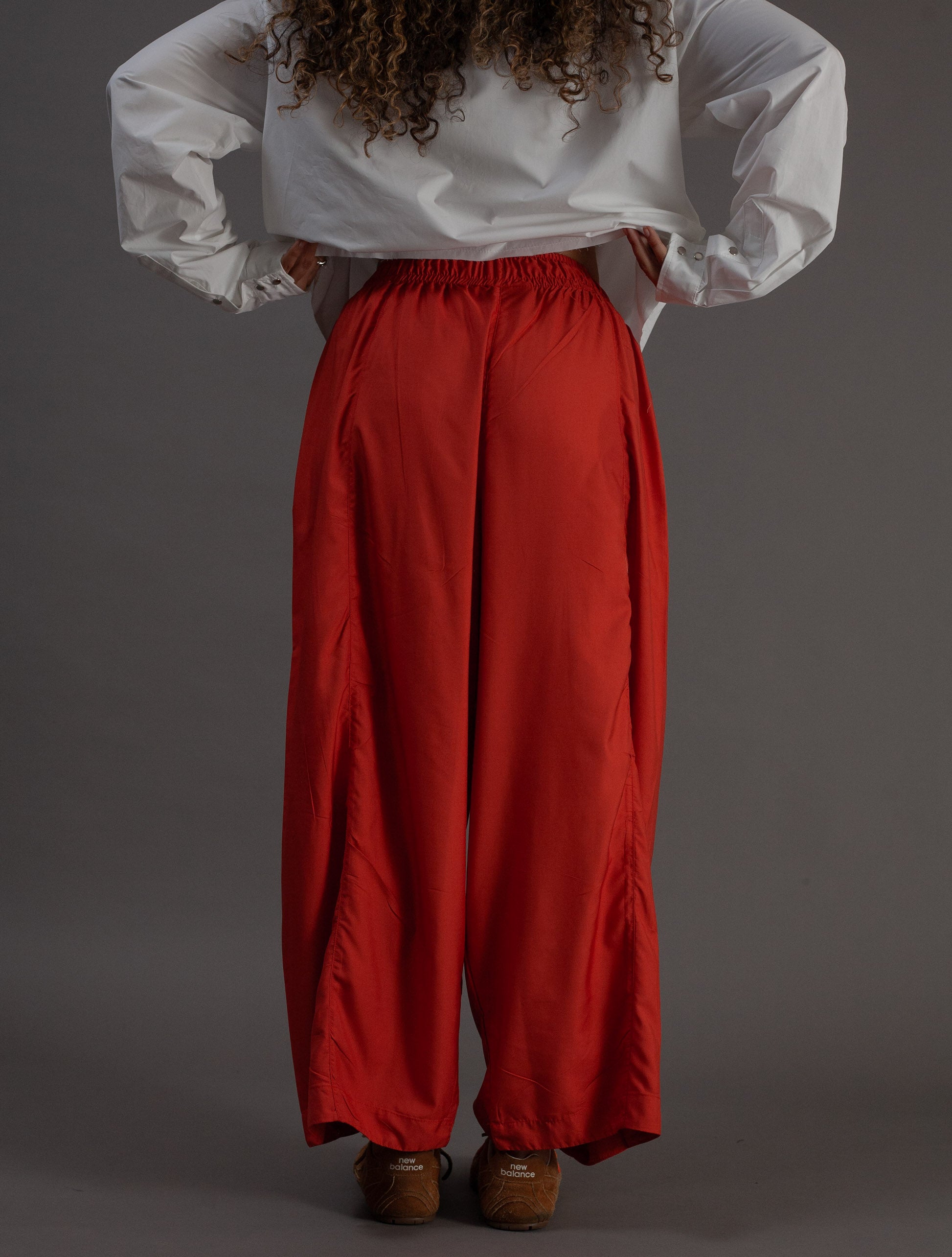 Person wearing a white shirt and orange pants on a gray background