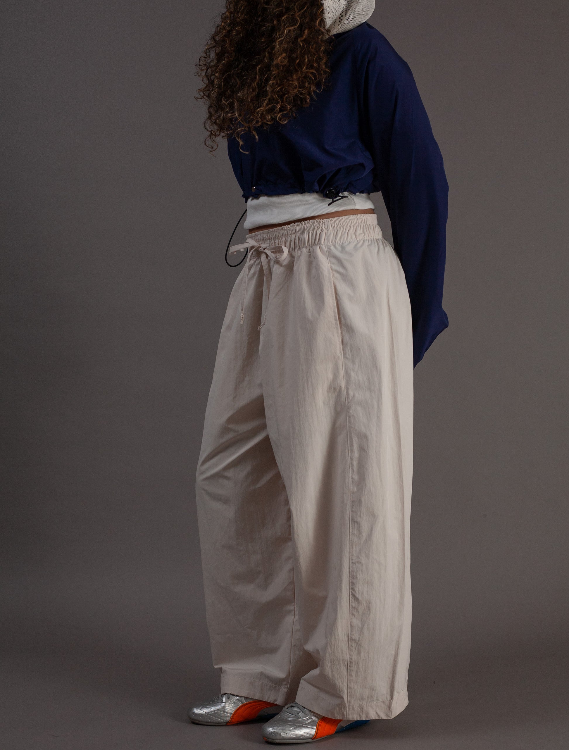 Person wearing a navy sweater and beige pants against a gray background