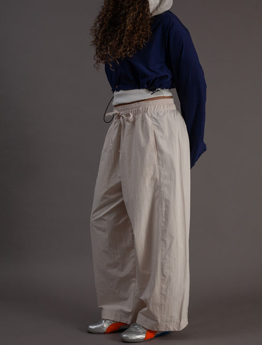 Person wearing a navy sweater and beige pants against a gray background