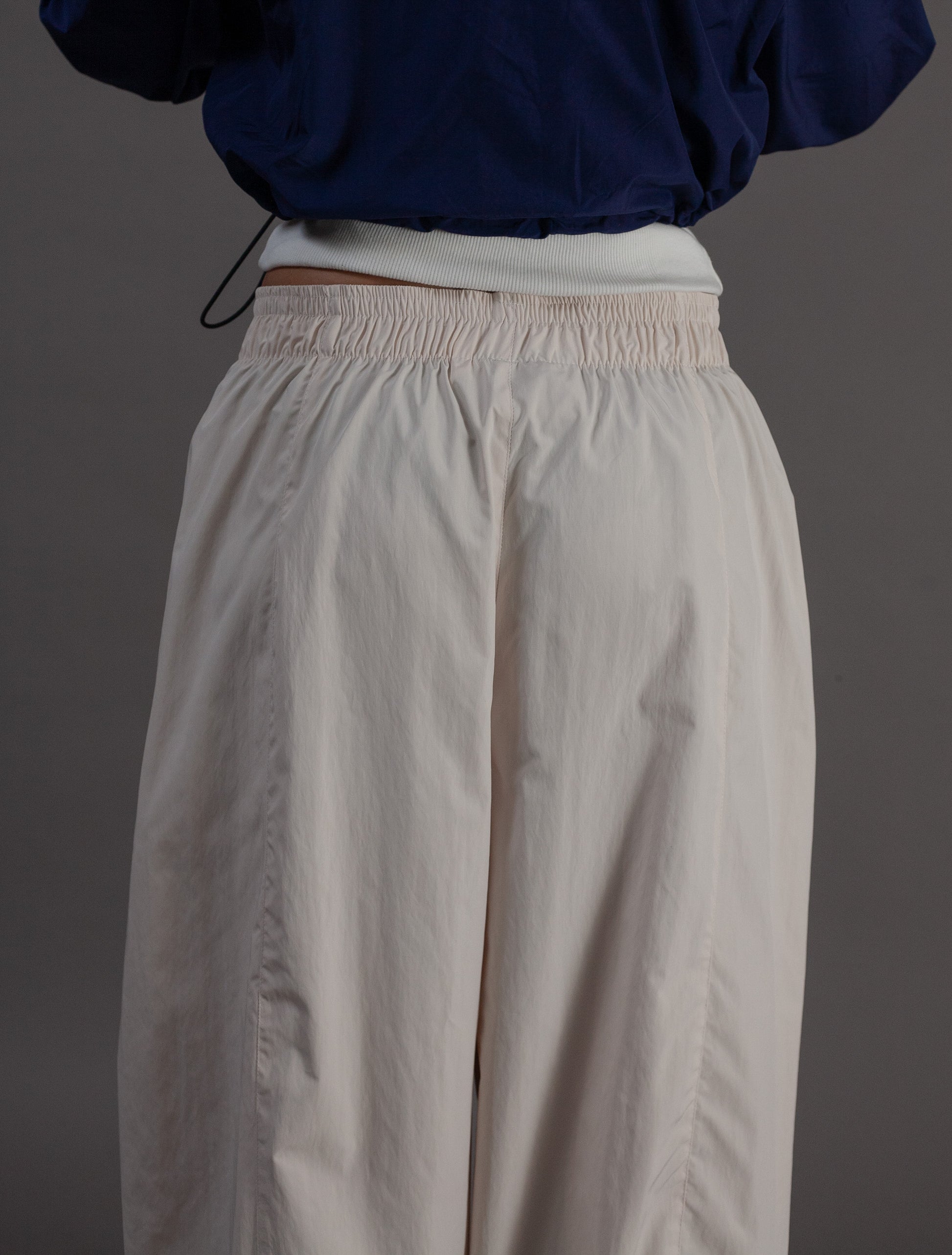 Beige pants worn with a navy top on a gray background