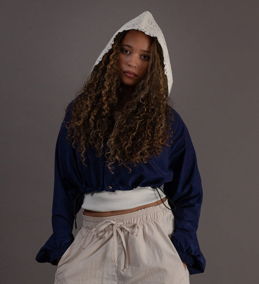 Person wearing a blue and white hoodie with beige pants on a gray background
