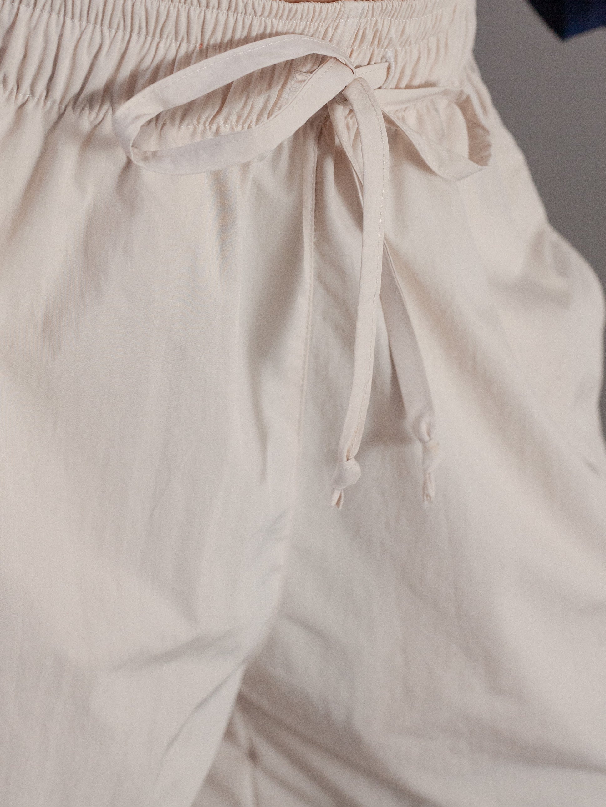 Close-up of beige pants with a drawstring waistband.