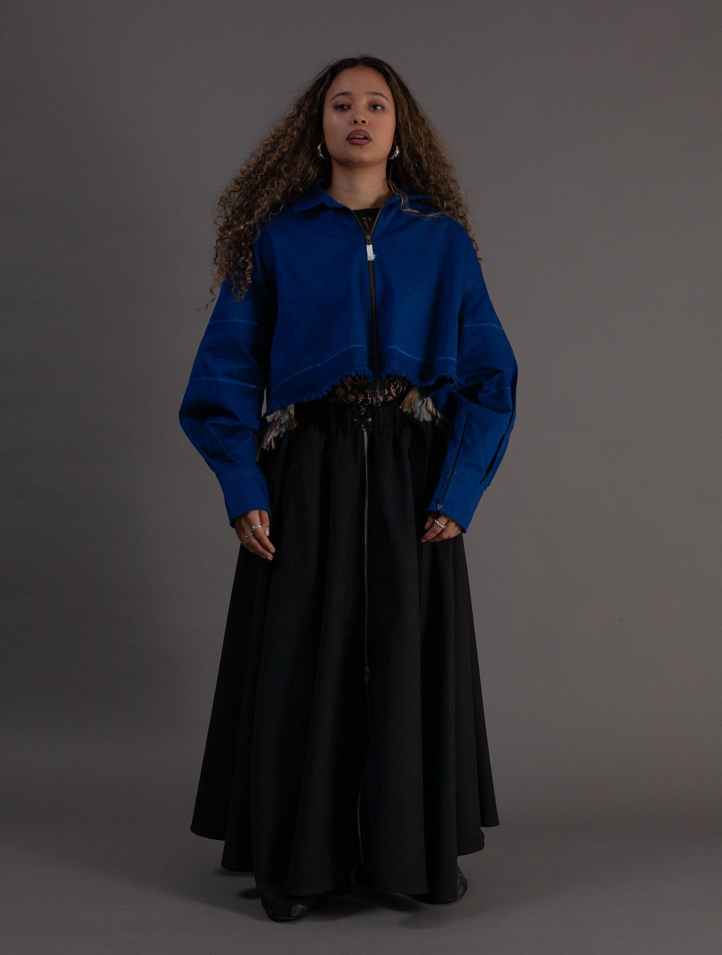 Woman wearing a blue jacket and black skirt against a gray background