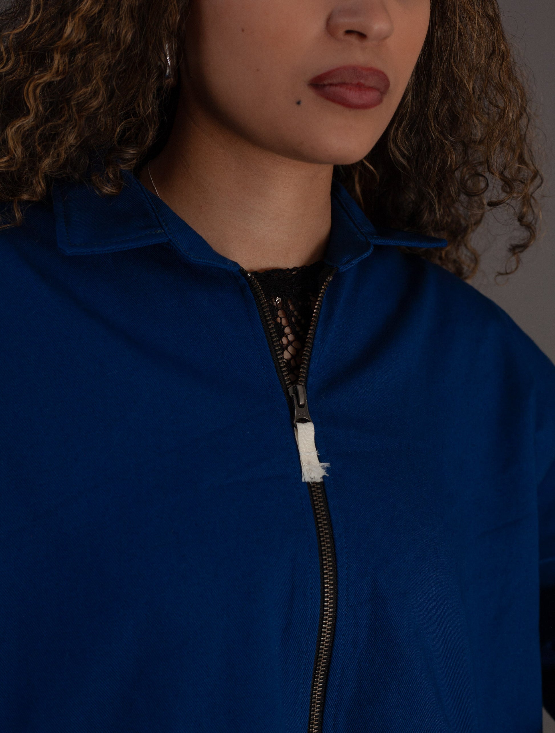 Close-up of a person wearing a blue jacket with a zipper.