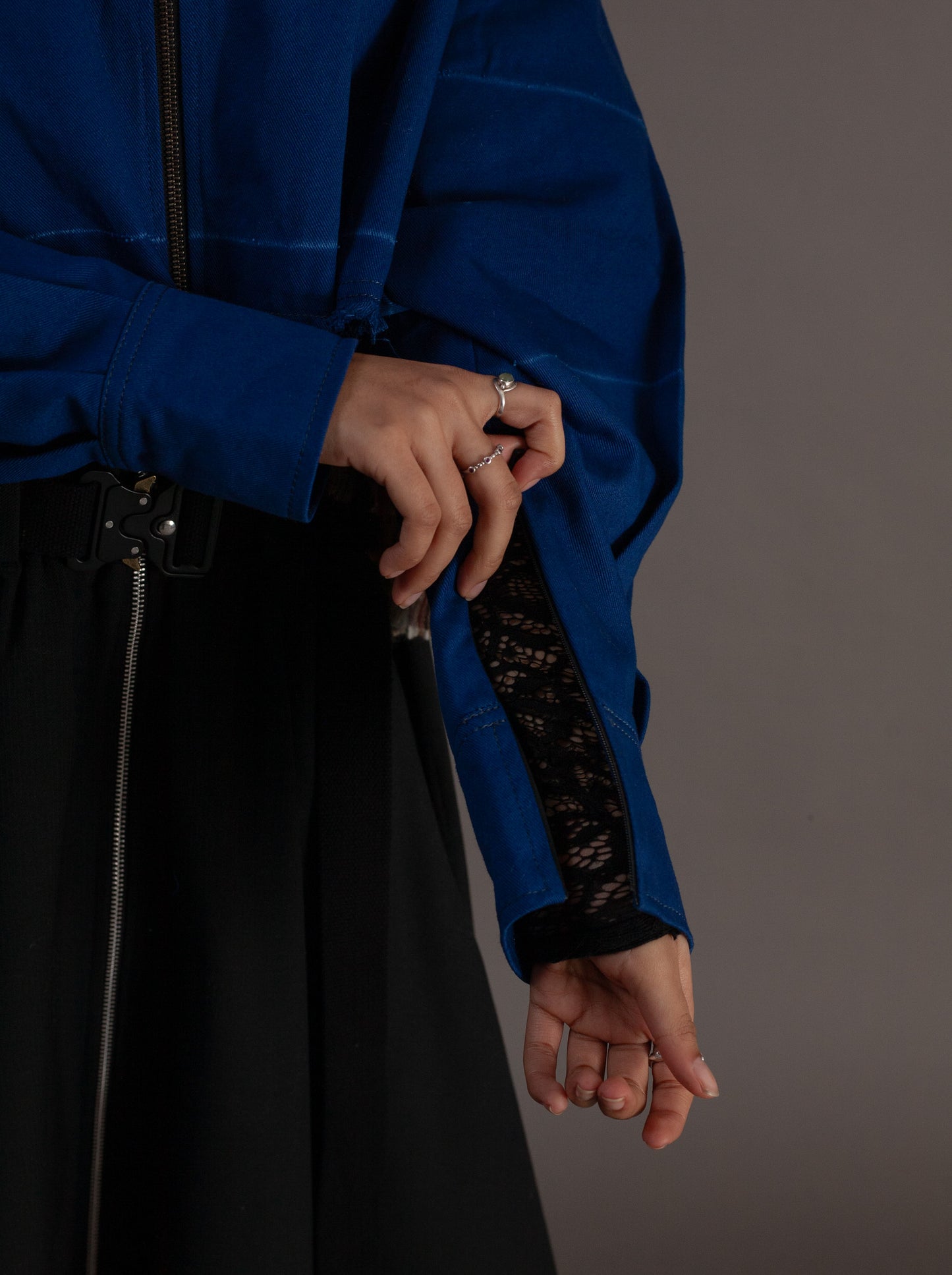 Person wearing a blue jacket with black mesh sleeves against a gray background