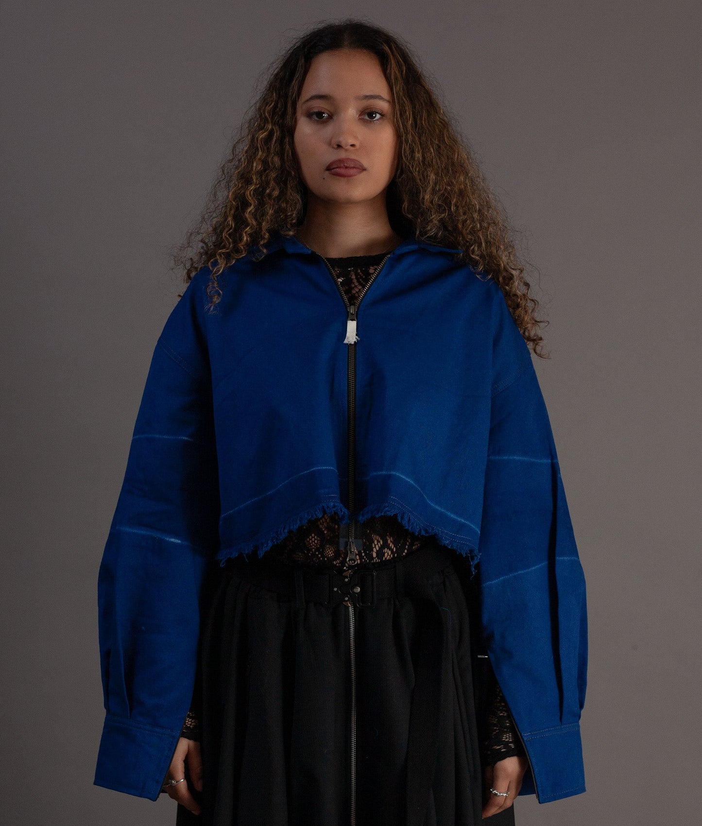 Woman wearing a blue jacket over a black outfit on a gray background