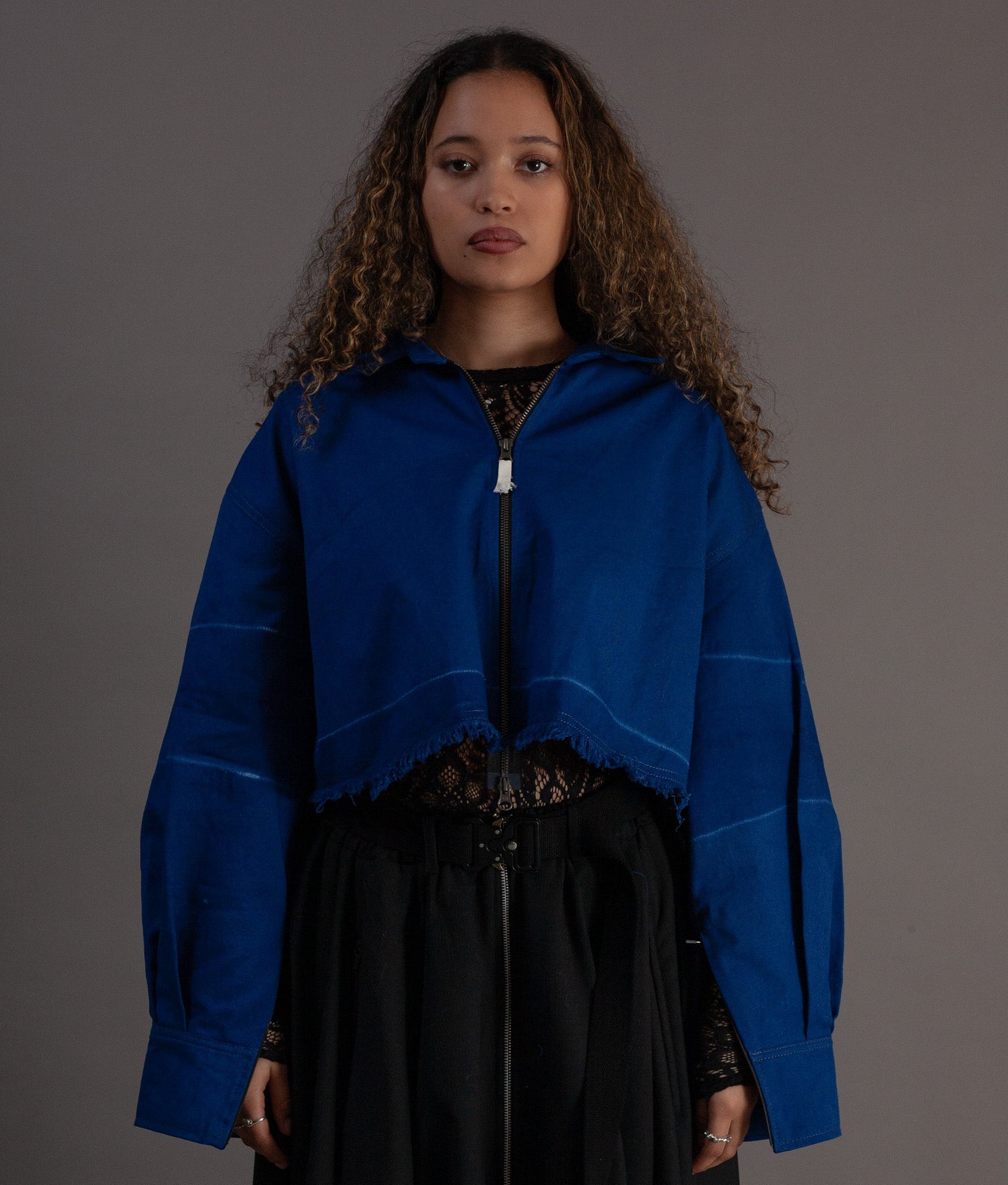 Woman wearing a blue jacket over a black outfit on a gray background