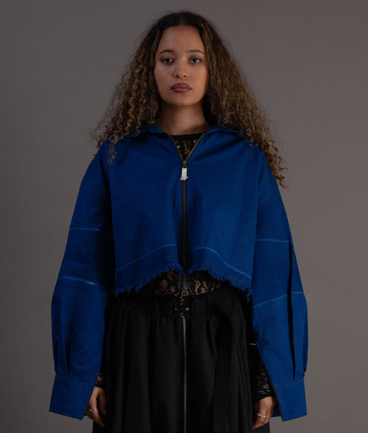 Woman wearing a blue jacket over a black outfit on a gray background