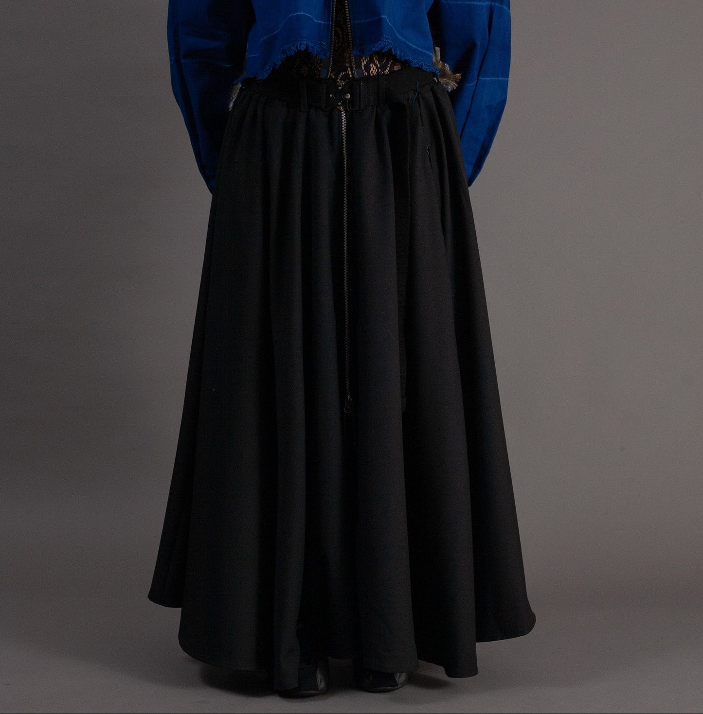 Person wearing a blue jacket and black skirt on a gray background