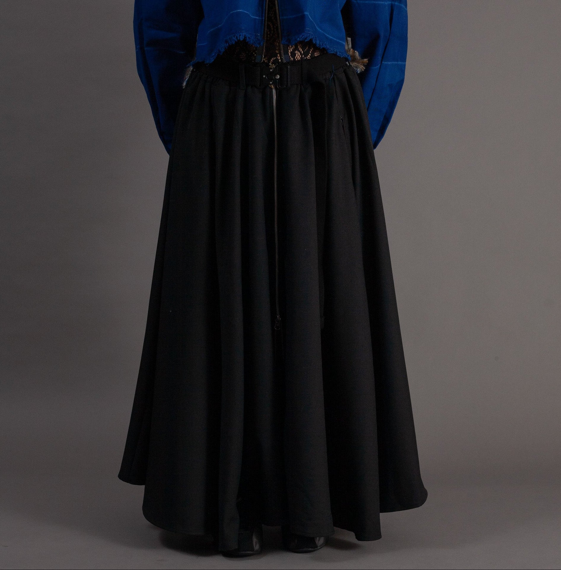Person wearing a blue jacket and black skirt on a gray background