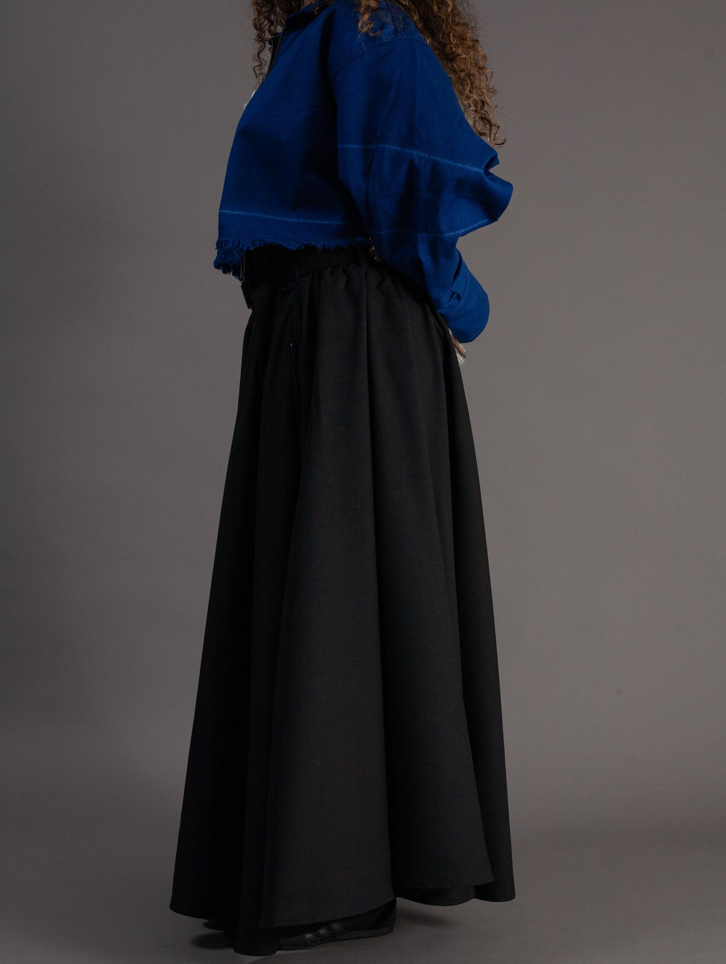 Person wearing a blue top and black skirt on a gray background