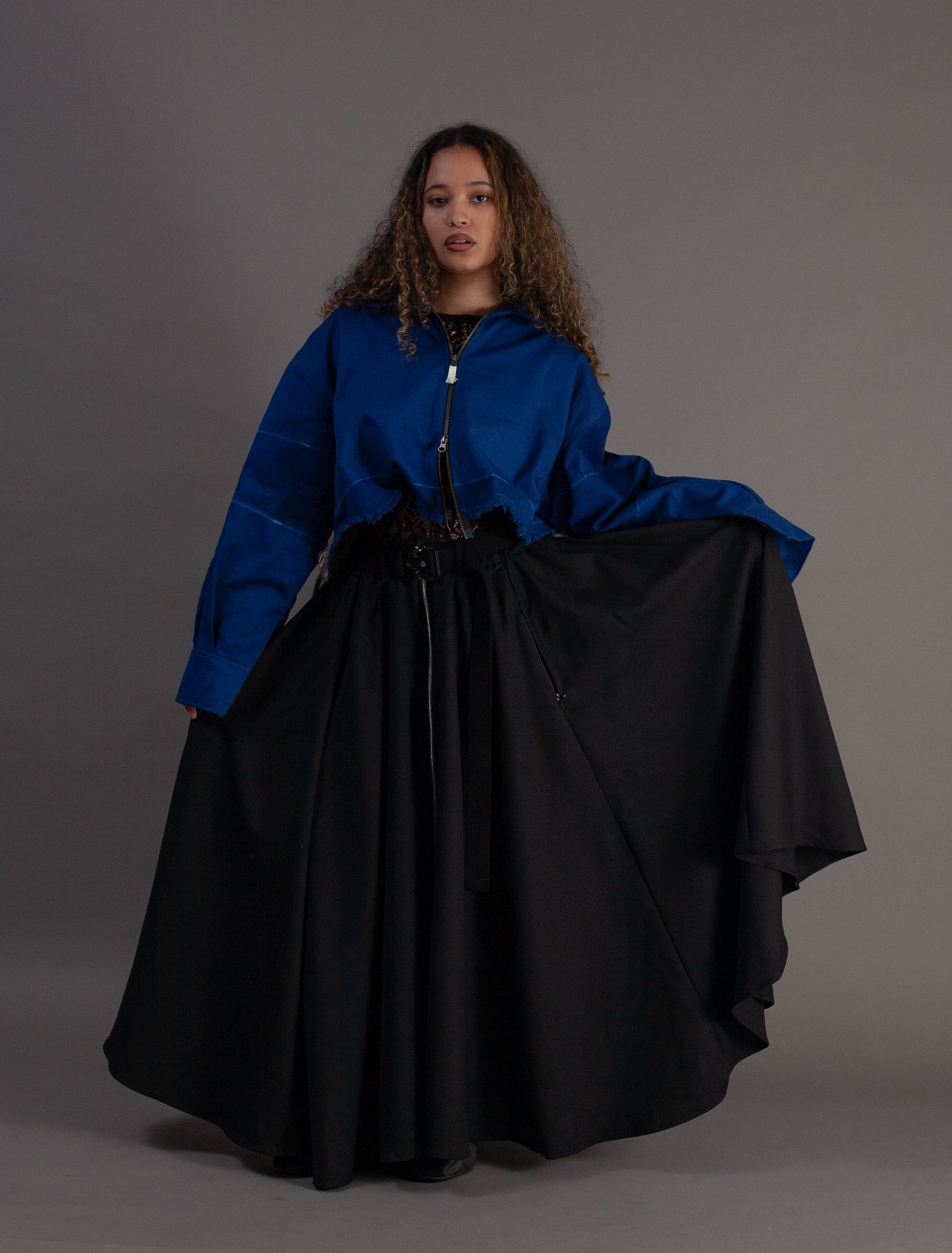 Woman wearing a blue jacket and black skirt against a gray background