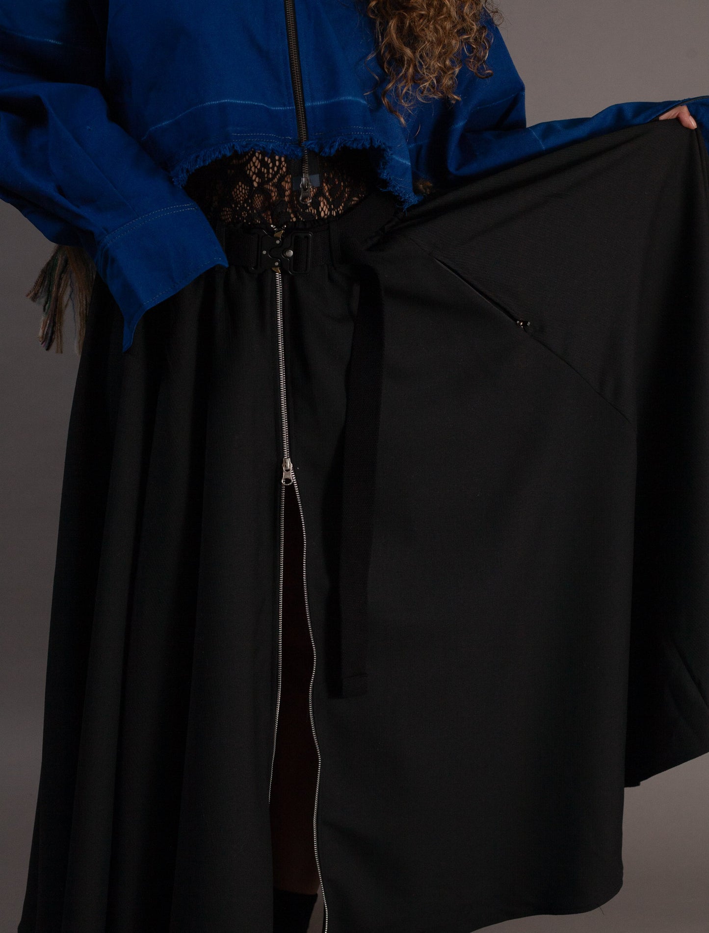 Person wearing a blue jacket and black skirt against a gray background
