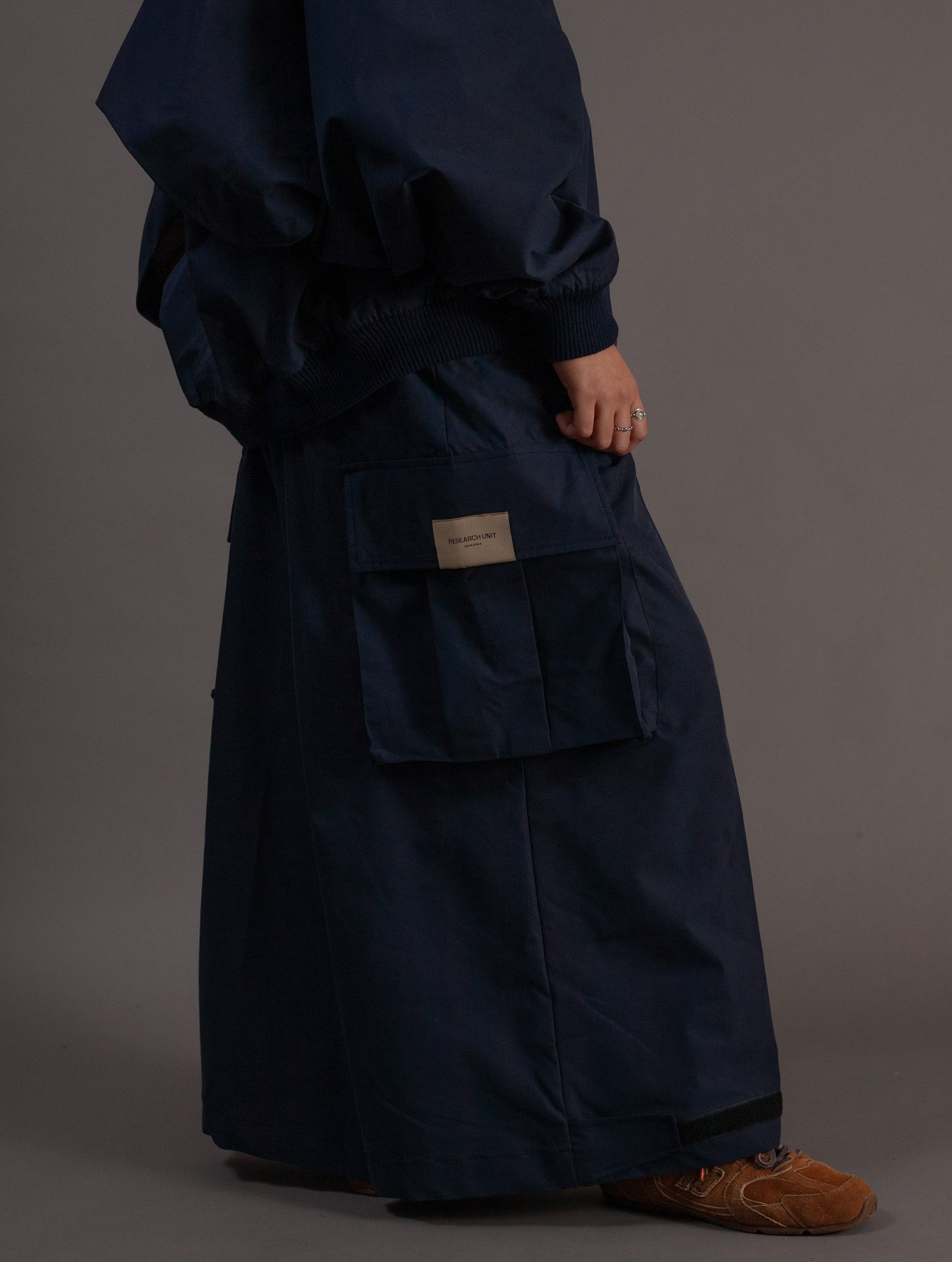 Person wearing a navy outfit with a visible brand label on a gray background