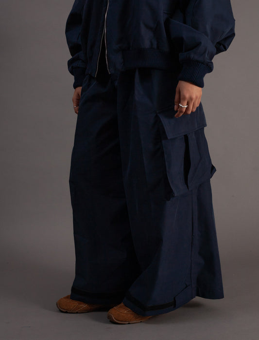 Person wearing a dark blue outfit with a long pants on a gray background