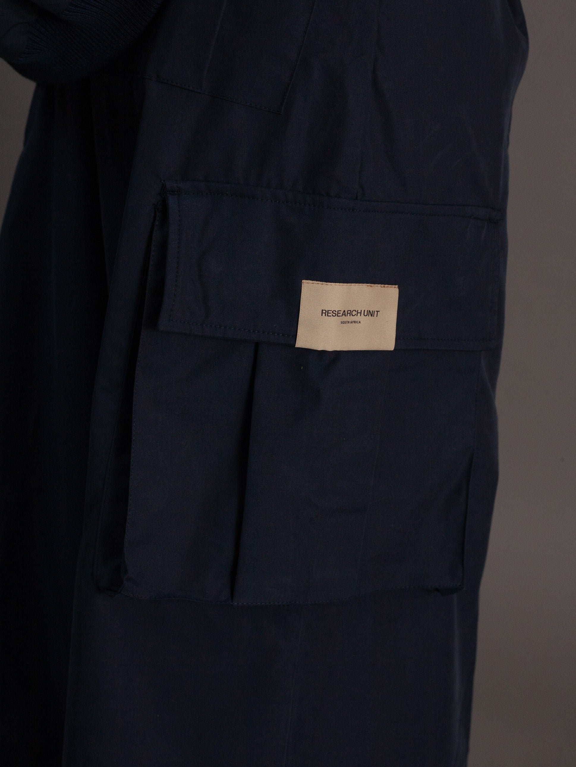 Navy blue pants with a beige label on a dark background