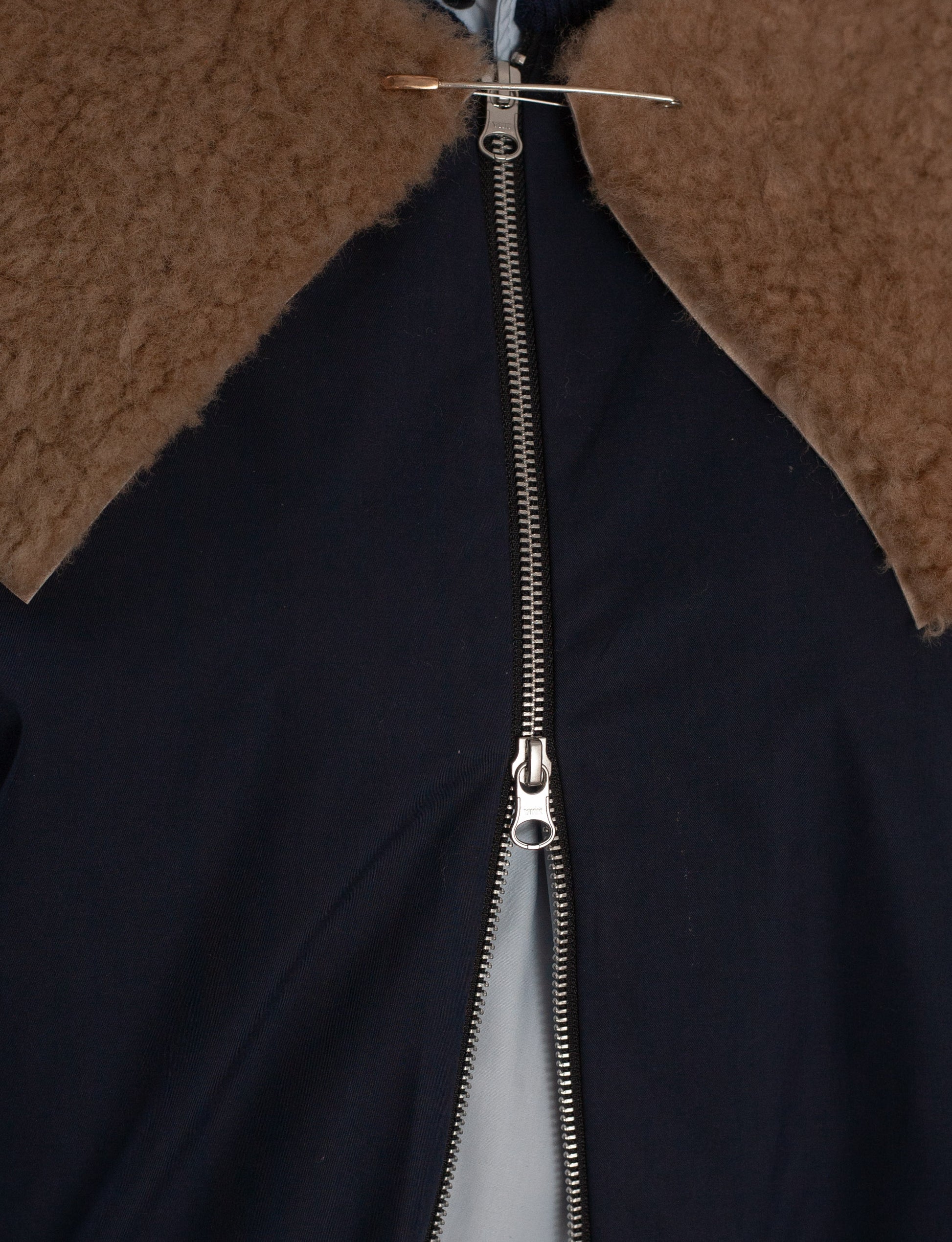Close-up of a black jacket with a brown fur collar and zipper