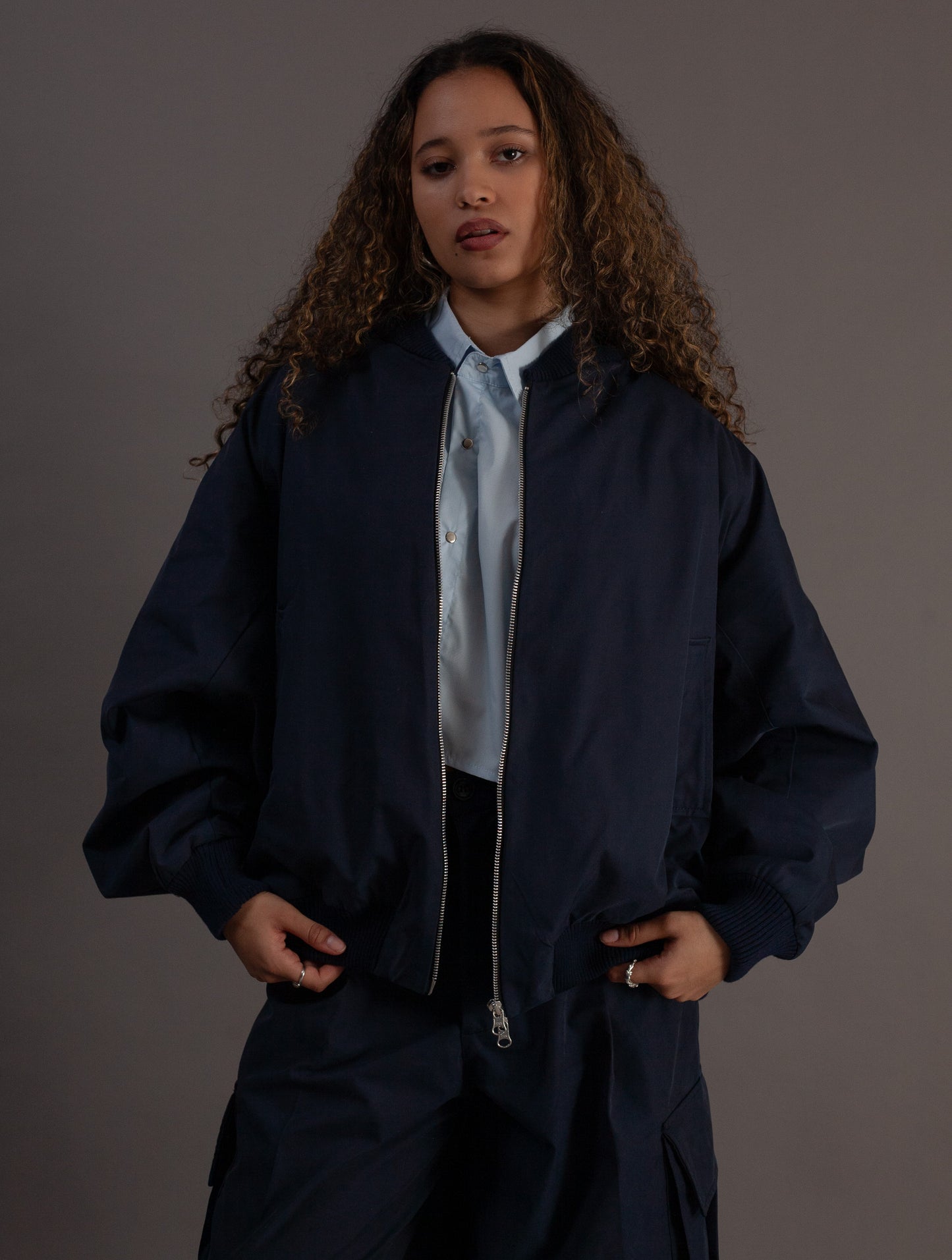 Person wearing a navy blue jacket over a light shirt on a gray background