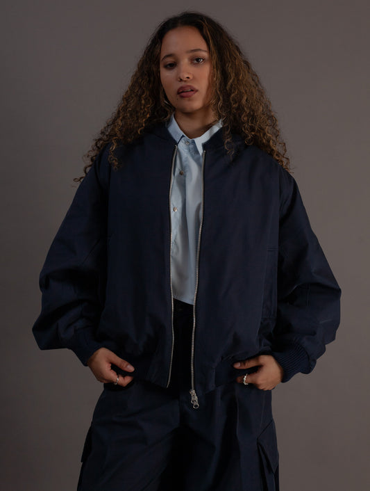 Person wearing a navy blue jacket over a light shirt on a gray background