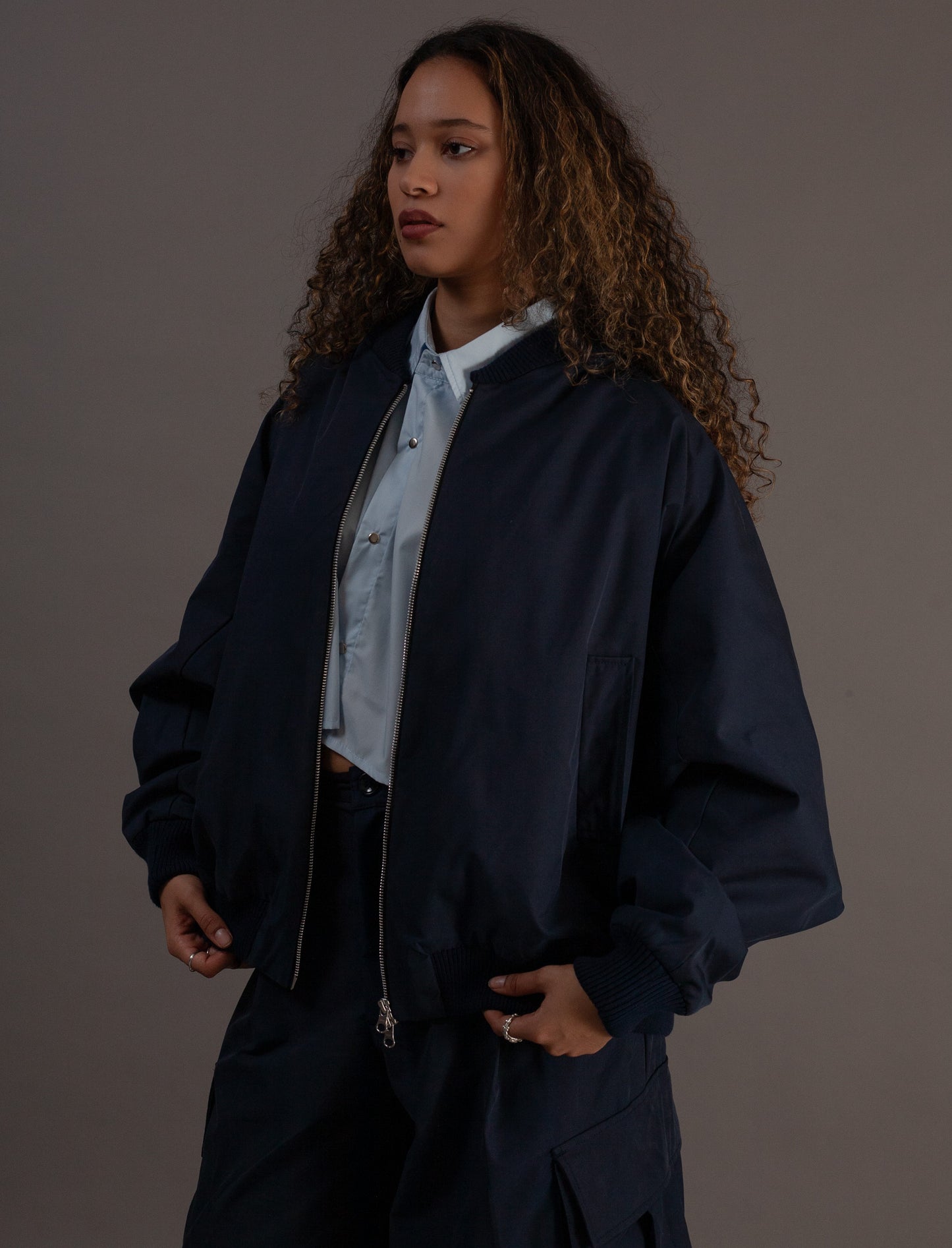 Person wearing a navy jacket over a light blue shirt on a plain background