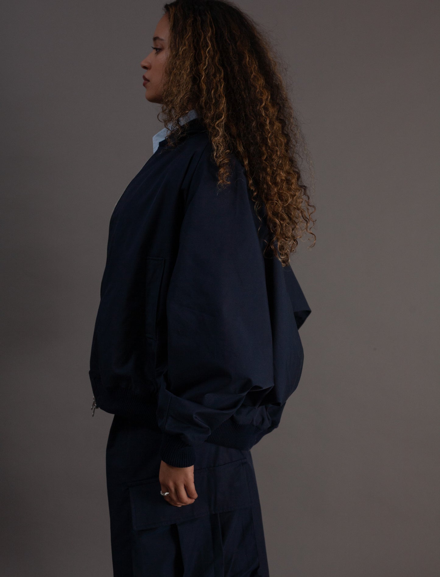 Person wearing a dark blue outfit against a gray background