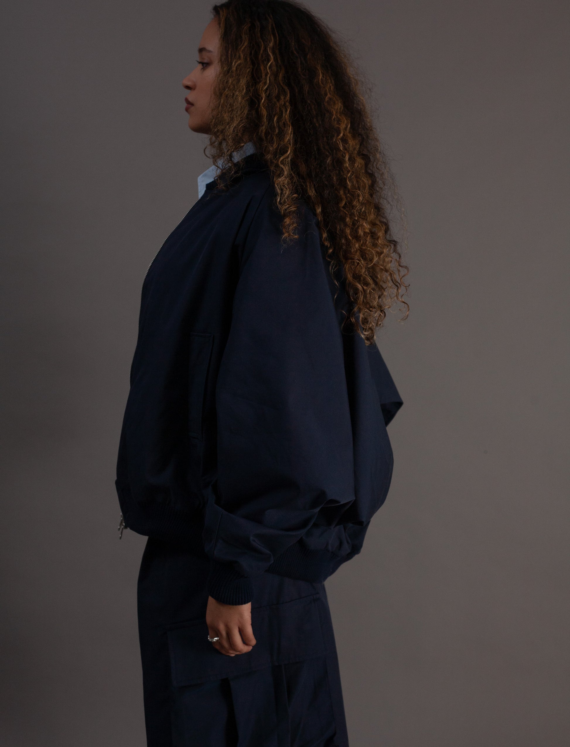Person wearing a dark blue outfit against a gray background